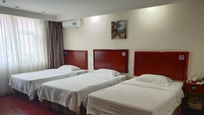 A hotel room with three single beds, a wooden headboard, a painting on the wall, and a telephone on the nightstand. - Greentree Inn Beijing Fengtai Dacheng Road Huanleshuimofang Business Hotel (Beijing)