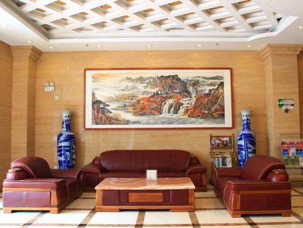 A lobby with a large painting, leather sofas, a coffee table, and two vases. - Greentree Inn Beijing Fengtai Dacheng Road Huanleshuimofang Business Hotel (Beijing)