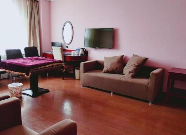 A room with a wooden floor, a sofa, a table with a mirror, a TV, and a window with curtains. - Greentree Inn Beijing Daxing Xingye Street Liyuan Business Hotel (Daxing)