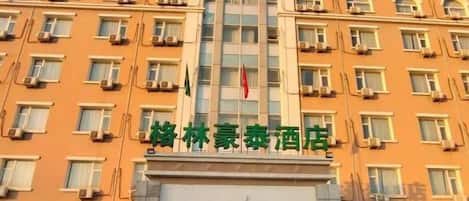 Un edificio de hotel de varios pisos con una entrada destacada y una bandera.