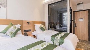 Ein Hotelzimmer mit zwei Betten, einem Nachttisch mit Telefon, einer Bedienungsanlage und einer Glastür zum Balkon.