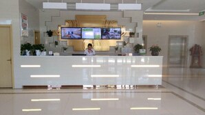 Una moderna reception con un televisore a schermo piatto che mostra una vista panoramica, un/una receptionist e un pavimento piastrellato pulito.