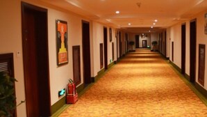 A long, narrow hotel corridor with doors on both sides, a patterned carpet, and a fire extinguisher on the left. - Greentree Inn Changzhi Bus Passenger Station Xihuan Road Business Hotel (Changzhi)