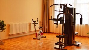 A home gym with an exercise bike, a multi-functional workout machine, and a radiator. - Greentree Inn Changzhi Bus Passenger Station Xihuan Road Business Hotel (Changzhi)