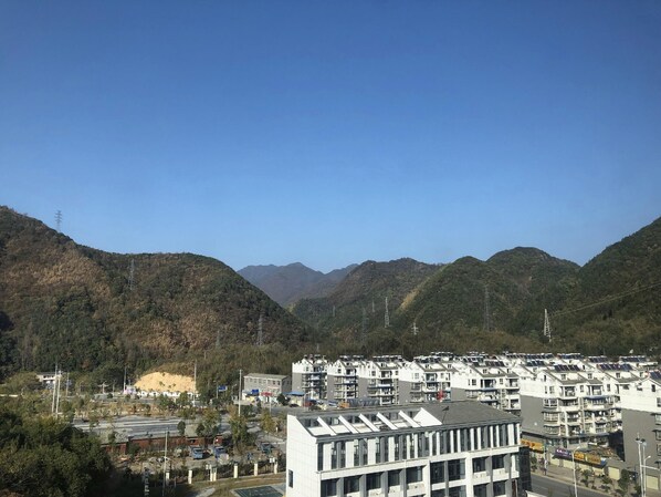 A residential area with modern apartment buildings, surrounded by hills and power lines. - Greentree Inn Chizhou Shitai County Zhengwu New District (Chizhou)