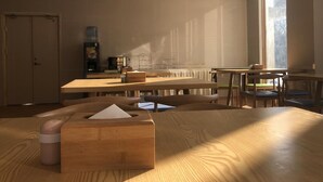 Une pièce spacieuse dotée de plusieurs tables et chaises en bois, d’un distributeur d’eau et d’une grande fenêtre laissant entrer la lumière naturelle.