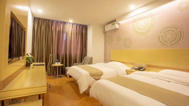 A hotel room with two beds, a desk, a chair, a small table with a plant, and a mirror. - Greentree Inn Chizhou Shitai County Zhengwu New District (Chizhou)