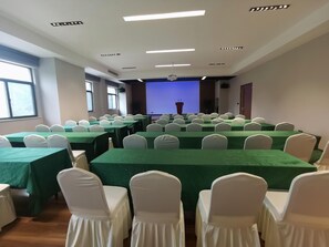 A conference room with multiple tables and chairs, a projector screen, and a podium. - Greentree Inn Chizhou Shitai County Zhengwu New District (Chizhou)