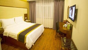 A hotel room with a bed, a desk, a chair, a TV, and a window with curtains. - Greentree Inn Fuyang Yijing International North Business (Fuyang)