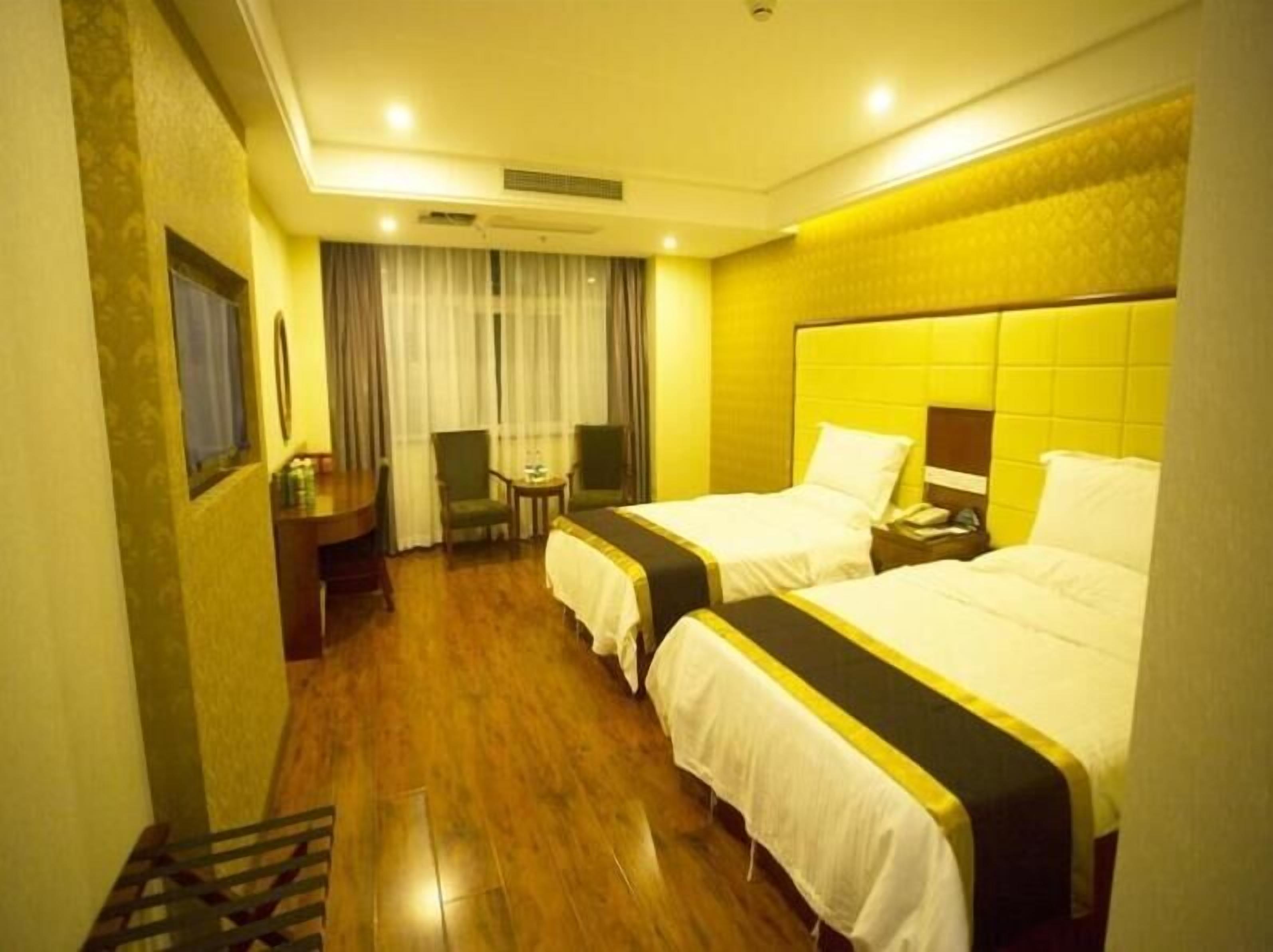 Quarto de hotel com duas camas, uma escrivaninha e uma cadeira.