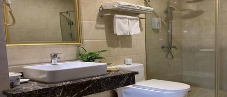 A modern bathroom with a large mirror, a sink, a toilet, and a glass-enclosed shower.