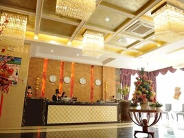 Zona de recepción de un hotel con mostrador, candelabros, relojes y un arreglo floral.