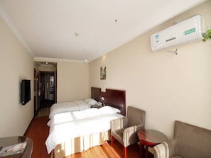 Une chambre d’hôtel avec deux lits, un canapé, une petite table et un appareil de climatisation.