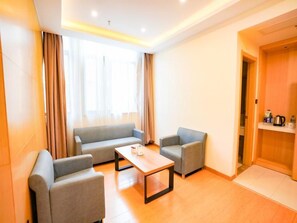 A modern hotel room with a sofa, two armchairs, a coffee table, and a wooden door. - Greentree Inn Hefei Fuyang Bei Road Beicheng Shuangfeng Industrial Park (Hefei)