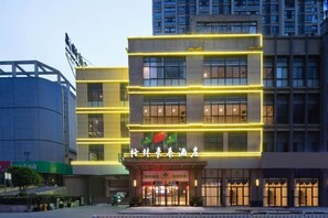 A hotel with a modern facade, illuminated signage, and a flag. - Greentree Inn Hefei Fuyang Bei Road Beicheng Shuangfeng Industrial Park (Hefei)