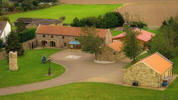 A stone building with a red-tiled roof, surrounded by a well-maintained lawn and a circular driveway.