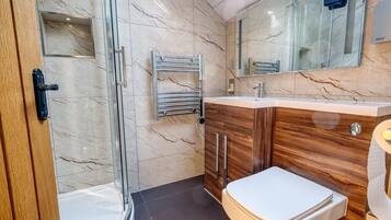 A modern bathroom with a glass shower enclosure, a wooden vanity with a white sink, and a toilet.