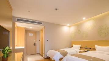 Ein Hotelzimmer mit zwei Betten, einem Schreibtisch und einer Zimmerpflanze.