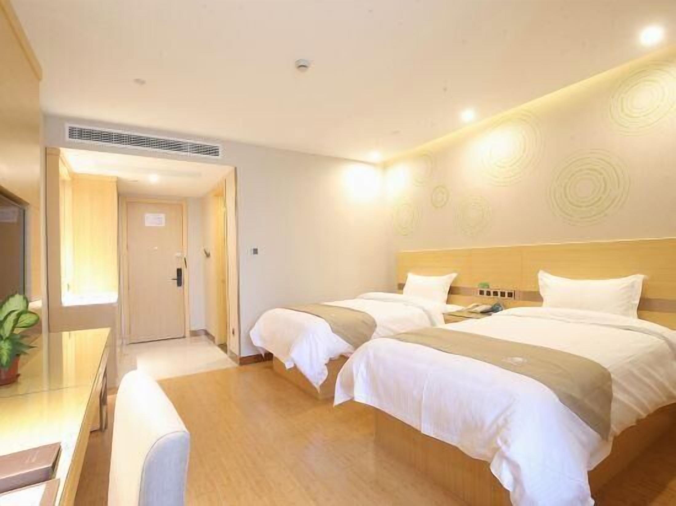 A hotel room with two beds, a desk, and a bedside table.
