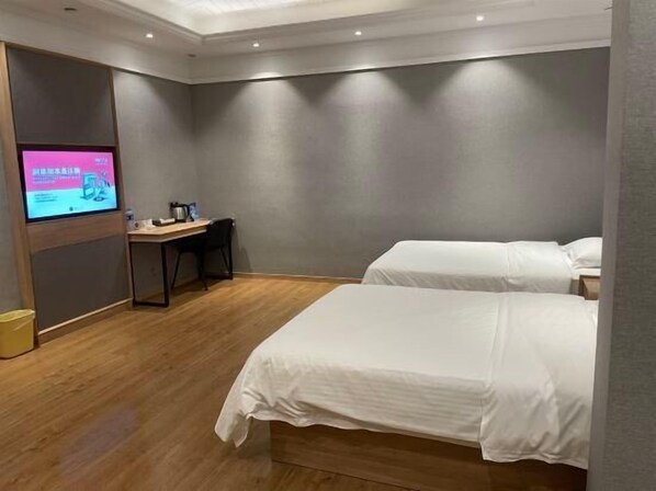 Une chambre d’hôtel avec deux lits, un bureau et un téléviseur fixé au mur.