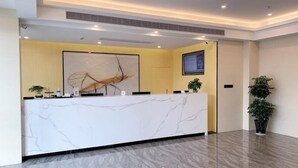 A reception desk with a marble top, a large abstract painting on the wall, and a potted plant to the right. - Green Tree Inn Huangshan Yi County Xidi Hongcun (Huangshan)
