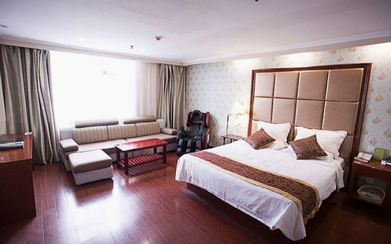 A hotel room with a large bed, a sofa, a small table, and a chair.
