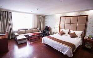 Una habitación de hotel con una cama grande, un sofá, una mesita y una silla.