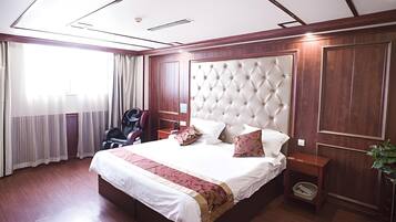 A hotel room with a large bed, a headboard, a desk, and a chair.