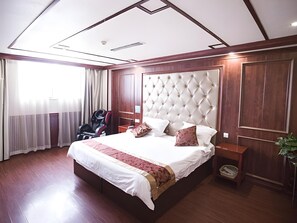 Hotellihuone, jossa on suuri sänky, pääty, työpöytä ja tuoli.