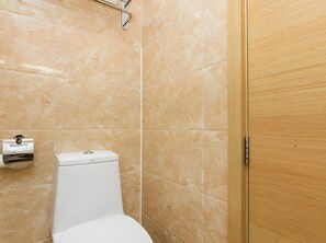 Et badeværelse med toilet, hårtørrer og en trædør.
