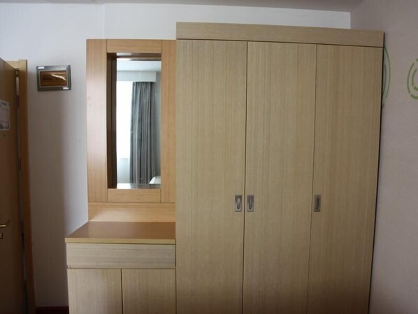 A room with a wooden wardrobe, a small mirror, and a framed item on the wall. - Greentree Inn Zaozhuang High-speed Train Station Express Hotel (Zaozhuang)
