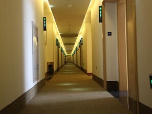 A long, narrow hotel corridor with doors on both sides, each marked with a green sign indicating room numbers. - Greentree Inn Zaozhuang High-speed Train Station Express Hotel (Zaozhuang)