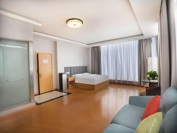 A hotel room with a bed, a desk, a sofa, and a large window with curtains. - Greentree Inn Zaozhuang High-speed Train Station Express Hotel (Zaozhuang)