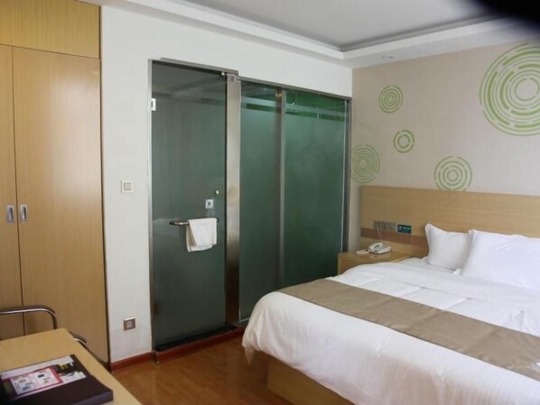 A hotel room with a bed, a nightstand, a phone, a towel on the door, and a wooden wardrobe. - Greentree Inn Zaozhuang High-speed Train Station Express Hotel (Zaozhuang)