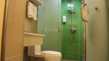 Casa de banho com sanita, chuveiro com porta de vidro e porta-toalhas.