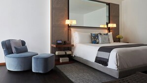A modern hotel room with a large bed, a desk with a laptop, a chair, and a small ottoman. - Las Alcobas A Luxury Collection Hotel Mexico City (Mexico City)