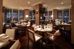 A restaurant with round tables, chairs, and a view of the cityscape through large windows. - Las Alcobas A Luxury Collection Hotel Mexico City (Mexico City)
