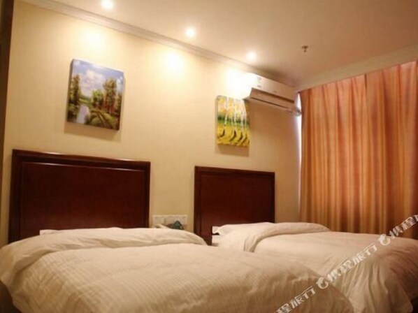 Habitación de hotel con dos camas, un cuadro en la pared, un equipo de aire acondicionado y una cortina en la ventana.