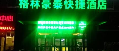 A hotel entrance with a neon sign in green.