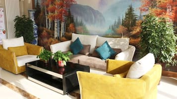 A living room with a sofa set, a coffee table, and decorative plants.