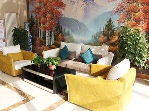 Sala de estar com sofá, mesa de centro e plantas decorativas.