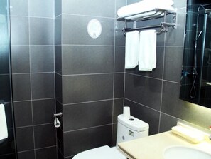 A modern bathroom with dark tiled walls, a toilet, a sink, and a shower area. - Greentree Inn Lvliang Xiaoyi City Fuqian Street Hotel (Lvliang)