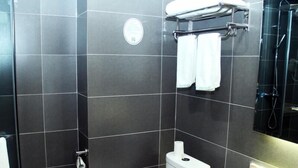 A modern bathroom with dark tiled walls, a toilet, a sink, and a shower area. - Greentree Inn Lvliang Xiaoyi City Fuqian Street Hotel (Lvliang)