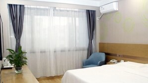 A hotel room with a bed, a desk, a chair, a potted plant, and a window with curtains. - Greentree Inn Lvliang Xiaoyi City Fuqian Street Hotel (Lvliang)