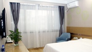 A hotel room with a bed, a desk with a plant, a chair, and a phone on the desk. - Greentree Inn Lvliang Xiaoyi City Fuqian Street Hotel (Lvliang)