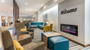 A modern hotel lobby with a 'Welcome' sign, comfortable seating, a fireplace, and a view into the dining area. - Mainstay Suites Murfreesboro, TN (Murfreesboro)