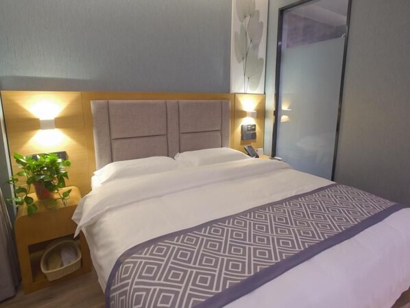 A hotel room with a bed, bedside table, lamp, and a wall-mounted phone. - Greentree Inn Puyang Ruifengyuan Business Hotel (Puyang)