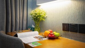 Habitación de hotel con un escritorio de madera, un florero, un frutero y un libro.