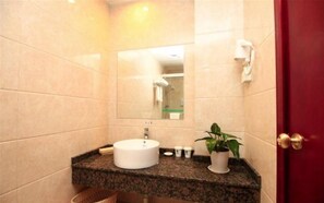 Um banheiro com uma pia redonda, um espelho, porta-toalhas e um vaso de planta.