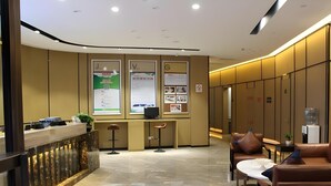 A modern hotel lobby with a reception desk, seating area, and lockers.